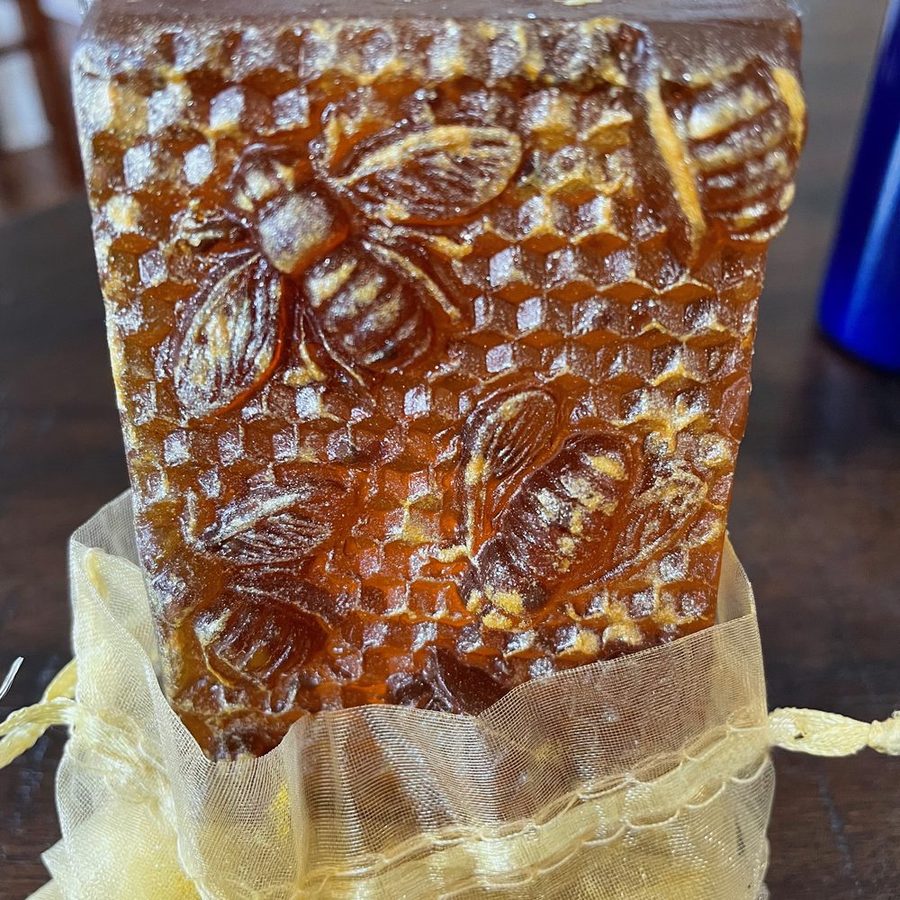 Amber honeycomb soap bar embossed with bees, resting in a gauze pouch